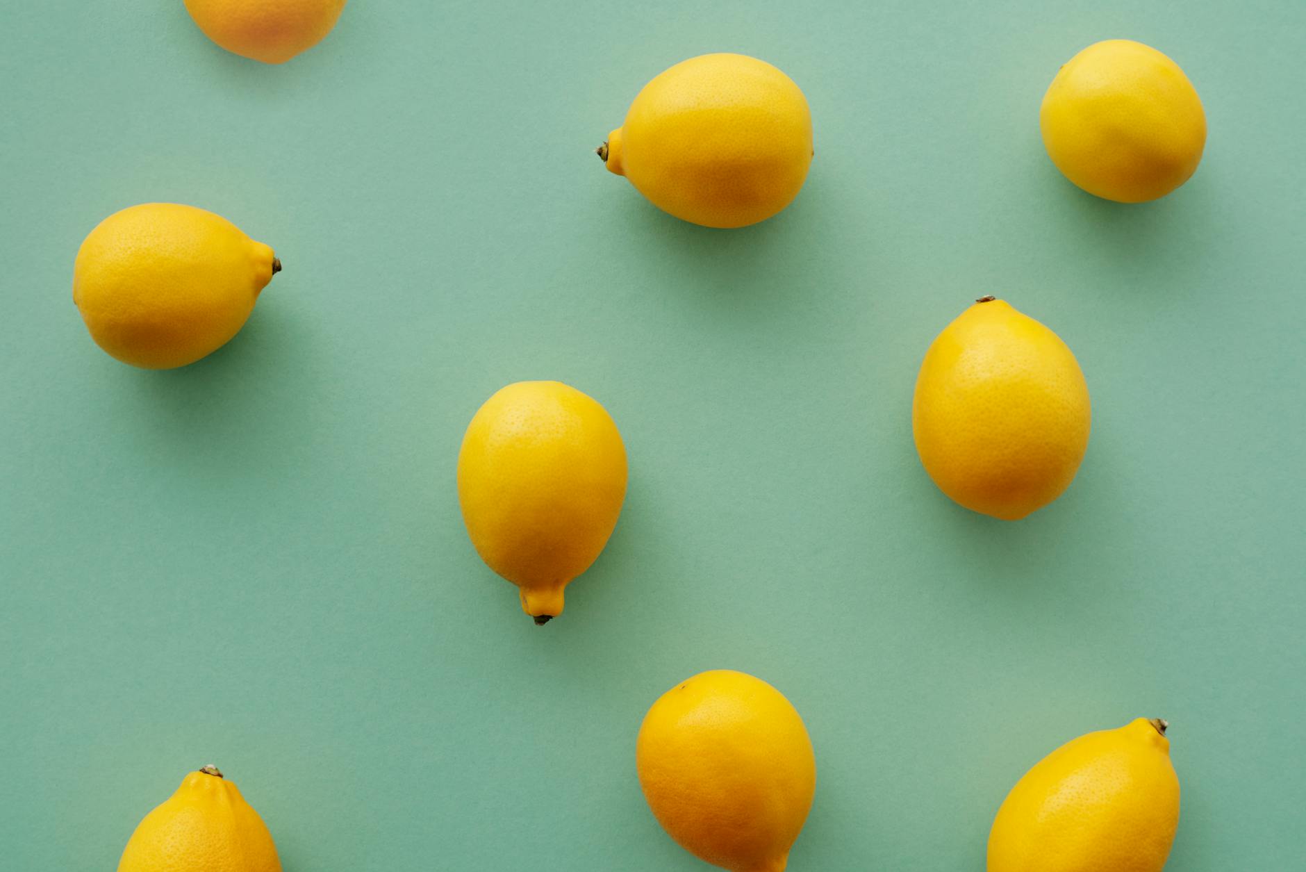 Bright yellow lemons arranged on a pastel green background, symbolizing fresh perspective on desire and pleasure.