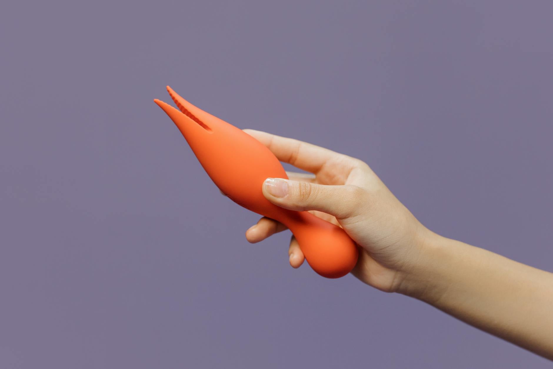 A hand holding a lemon-colored suction vibrator against a minimalistic backdrop, representing reconnection with pleasure.