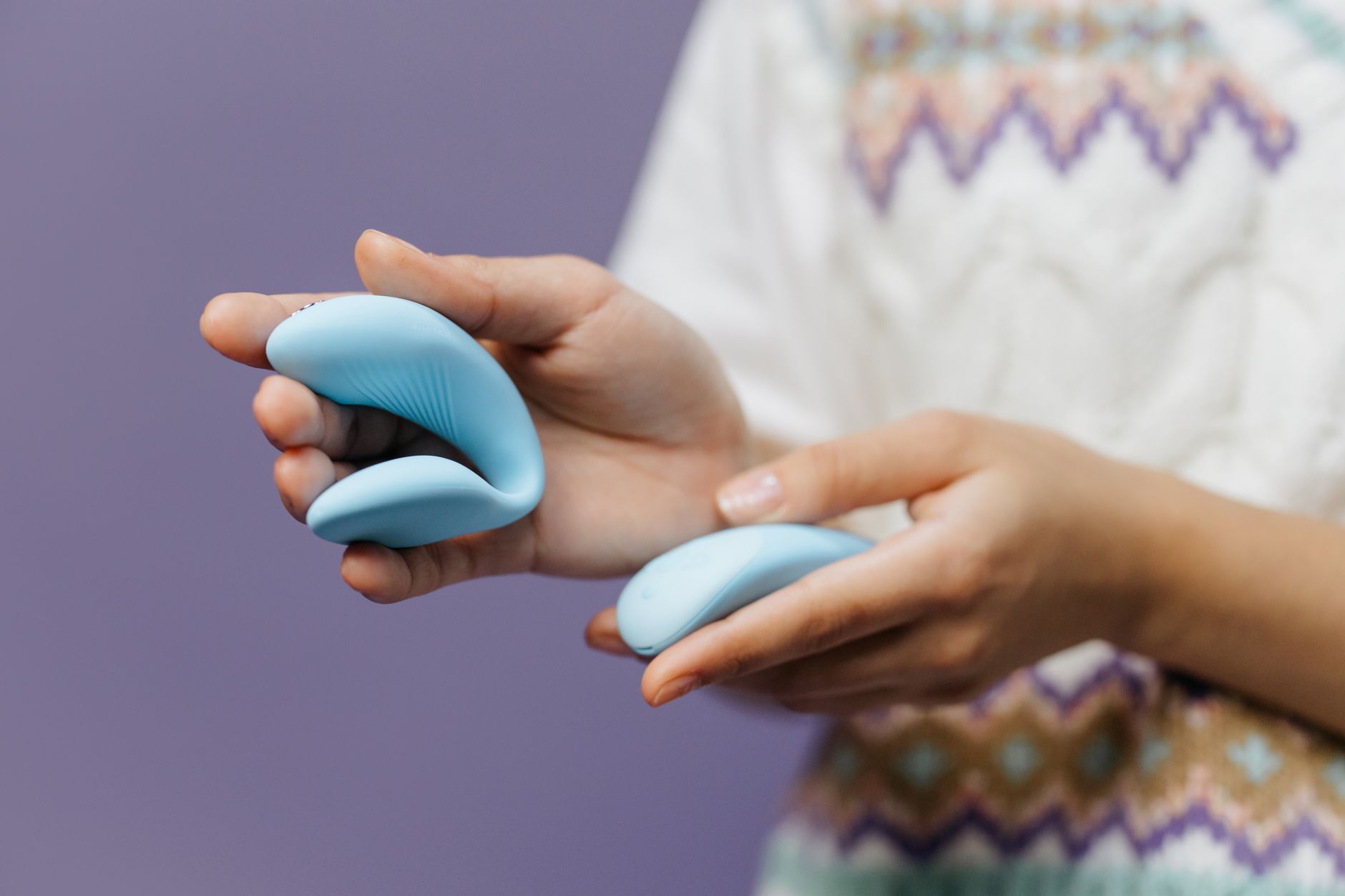 Close-up of hands holding a sleek lemon vibrator against a warm background