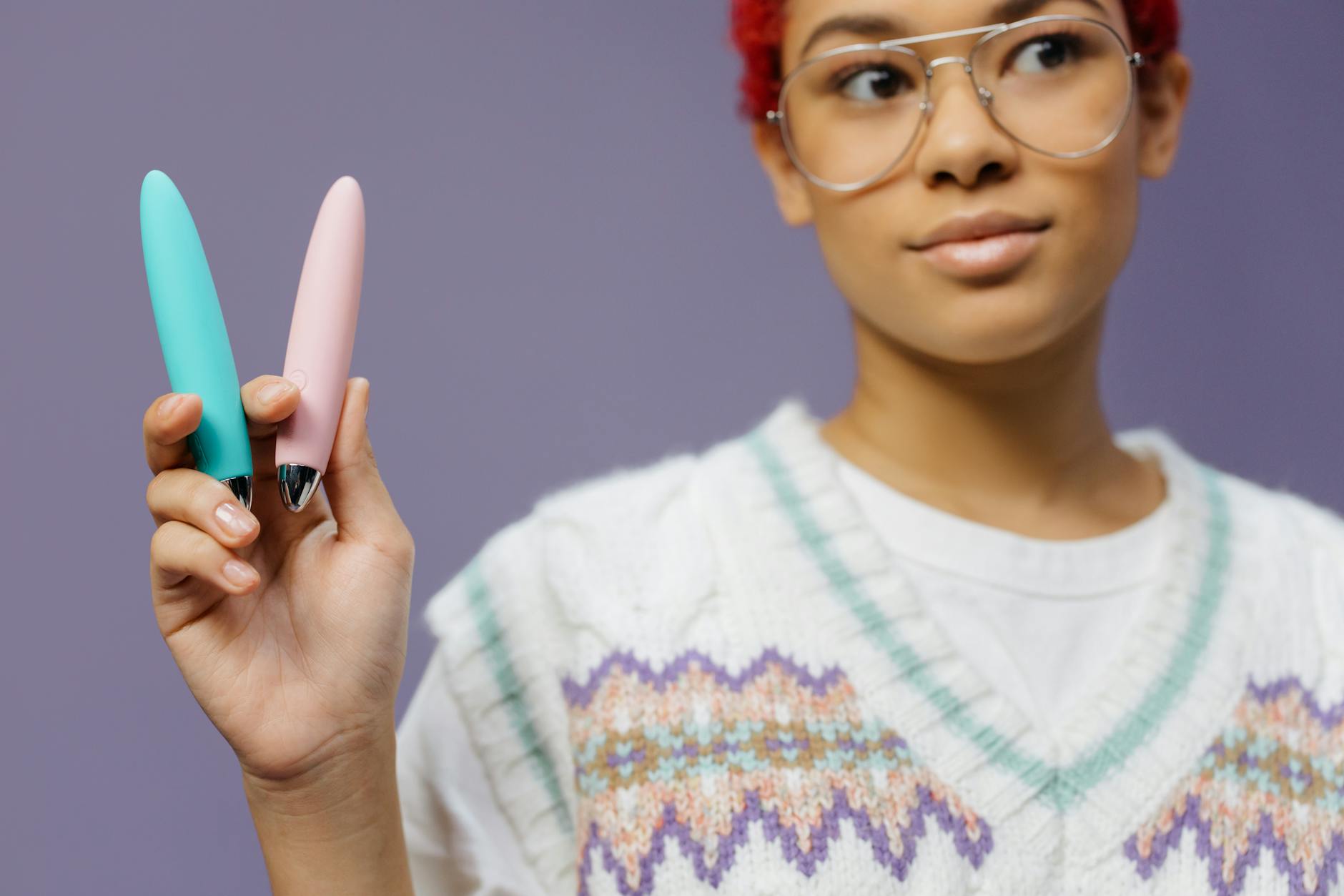 A person holding two vibrators against a purple background, representing midlife sexual exploration