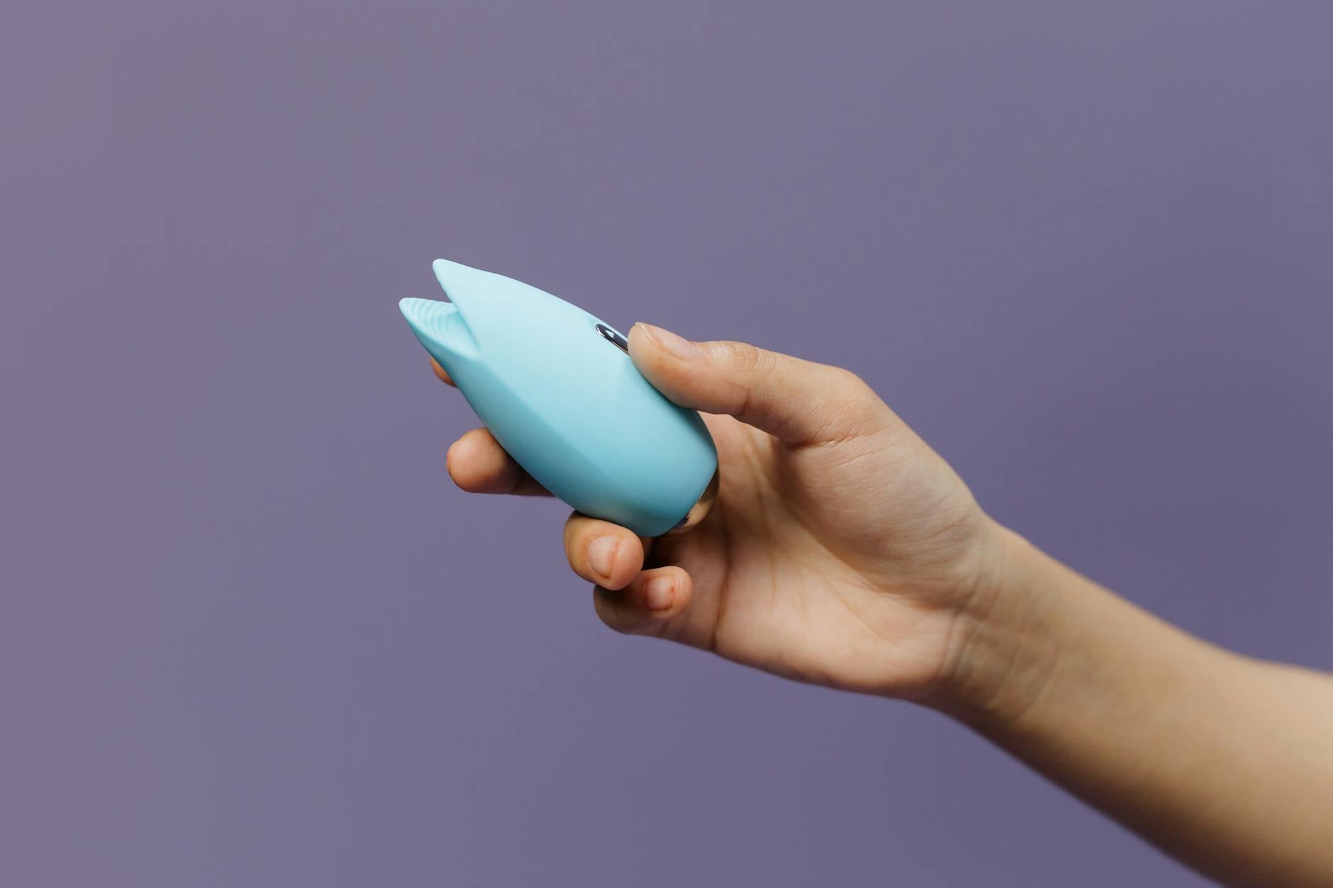 A teal lemon vibrator on smooth white silk fabric