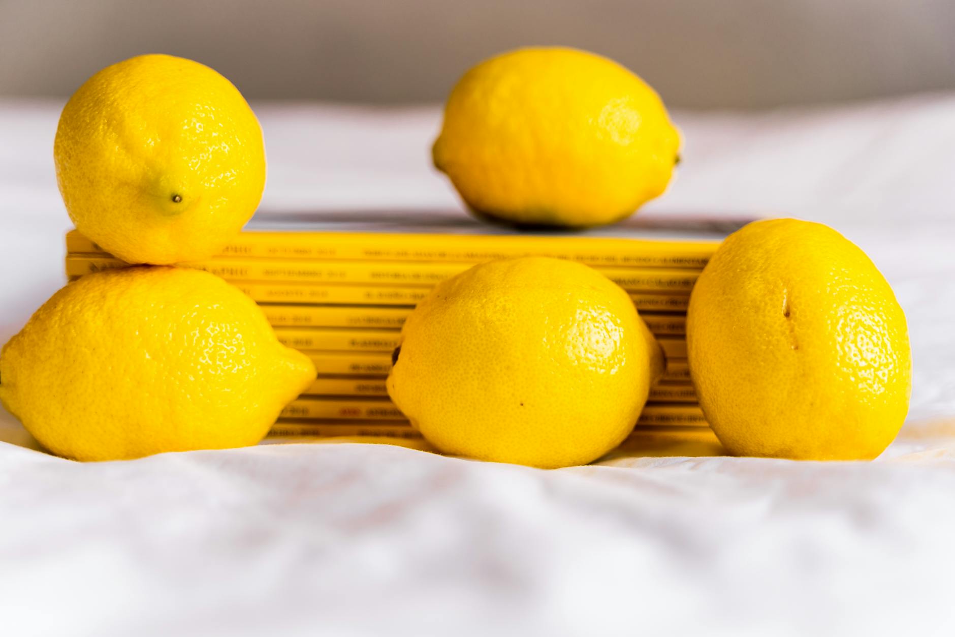 Fresh yellow lemons arranged with stacked books on white fabric, symbolizing natural hormonal rebalancing